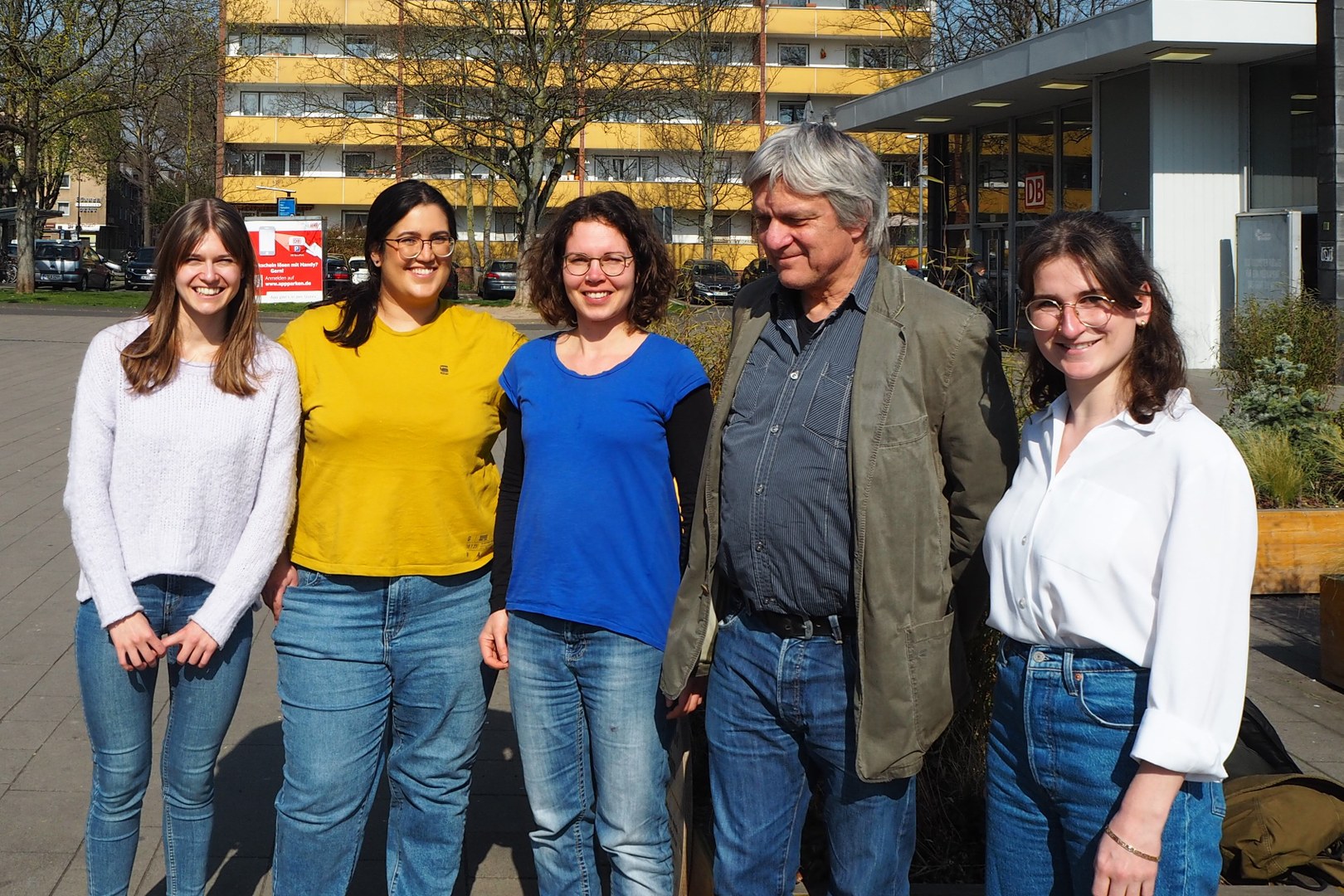 Eine Wissenschaftlerin und ein Wissenschaftler arbeiten hinter einer Glasfassade und mischen Chemikalien mit Großgeräten.