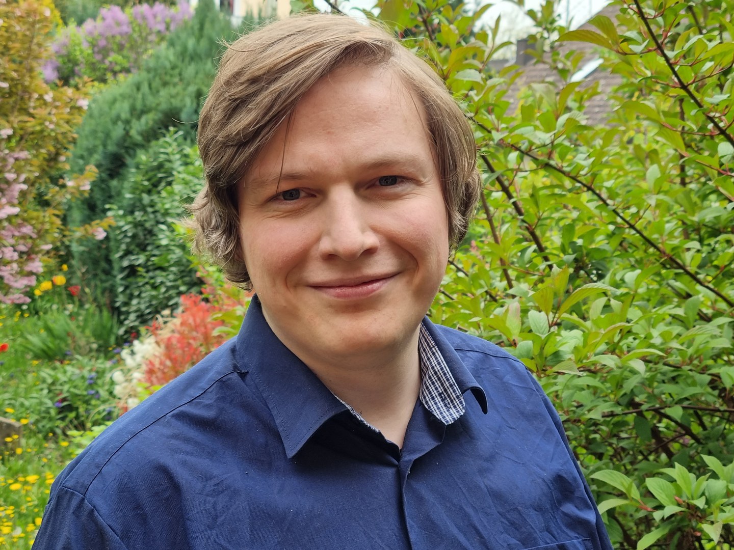 Eine Wissenschaftlerin und ein Wissenschaftler arbeiten hinter einer Glasfassade und mischen Chemikalien mit Großgeräten.