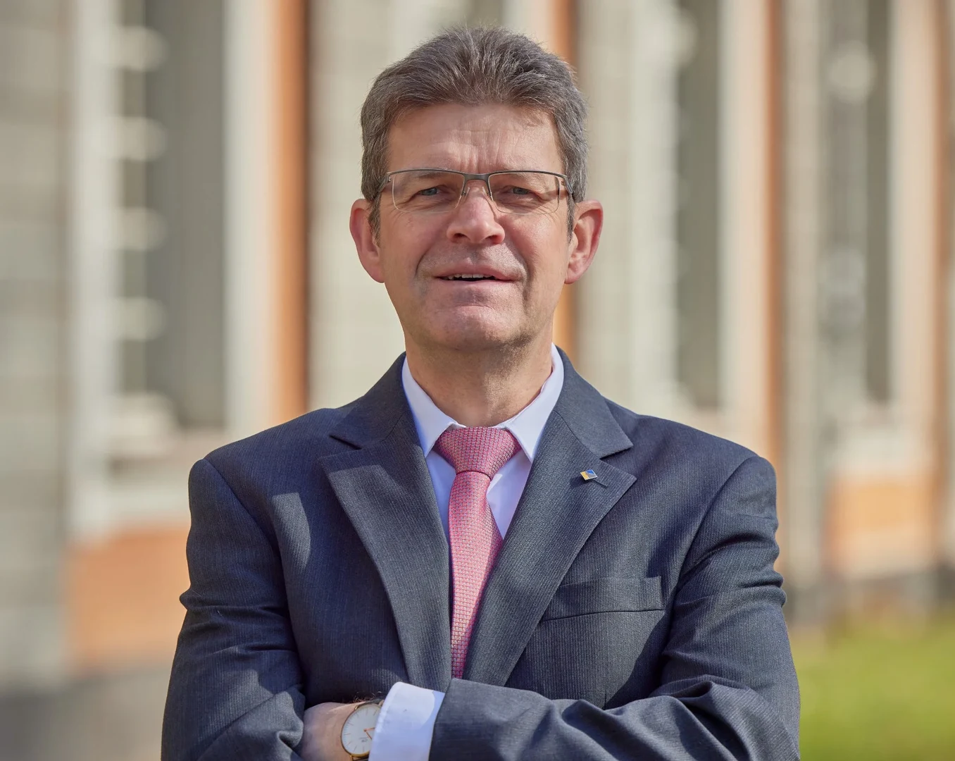 Eine Wissenschaftlerin und ein Wissenschaftler arbeiten hinter einer Glasfassade und mischen Chemikalien mit Großgeräten.