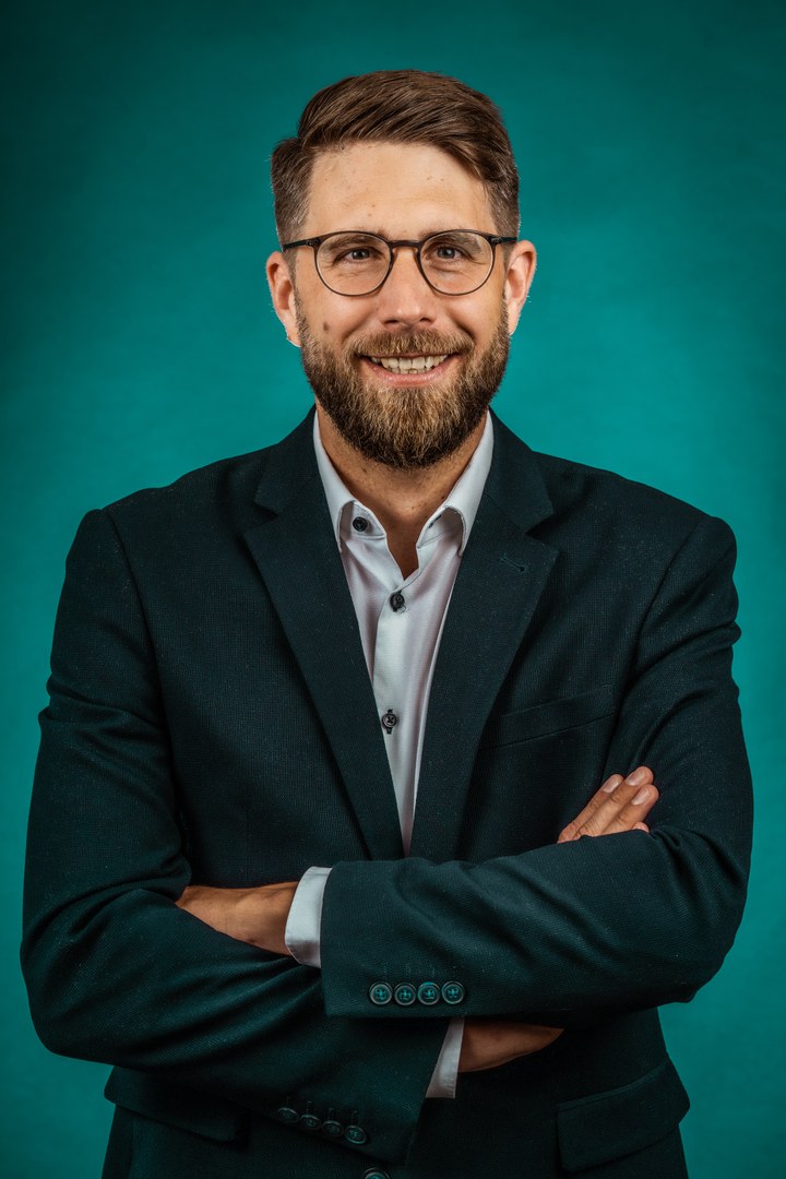 Eine Wissenschaftlerin und ein Wissenschaftler arbeiten hinter einer Glasfassade und mischen Chemikalien mit Großgeräten.